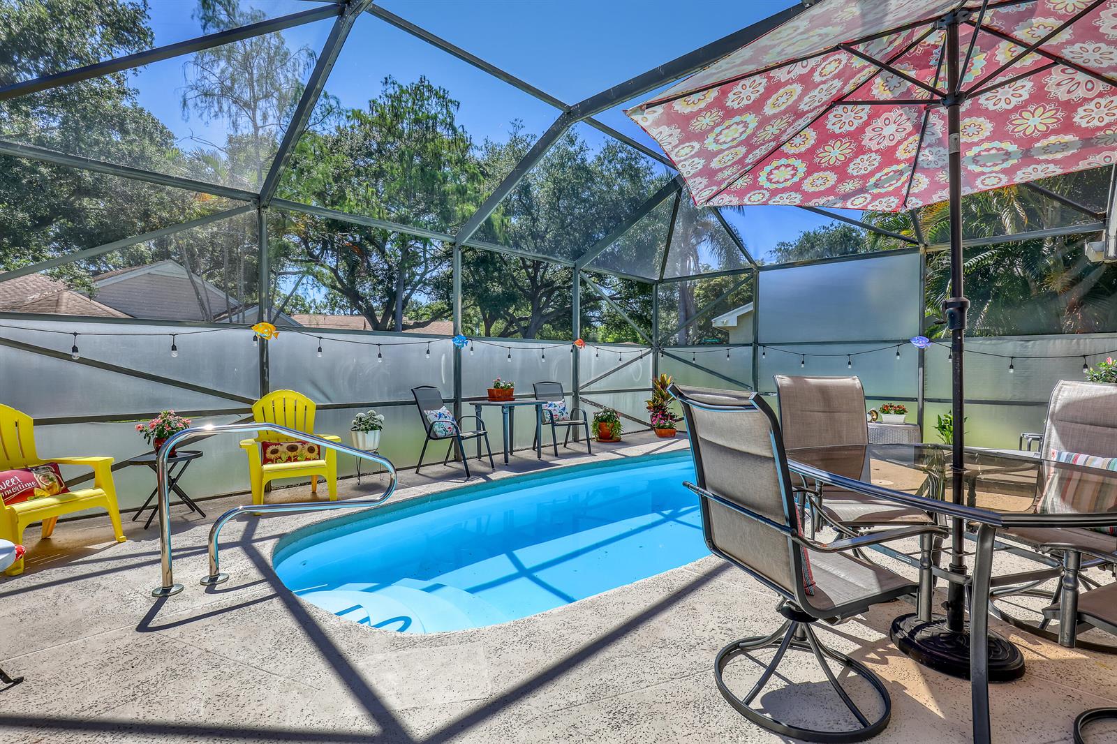 A screened-in patio features a small swimming pool, outdoor furniture, and a decorative umbrella — 4201 Green Forest Way, Boynton Beach FL 33436, BOYNTON BEACH, FL