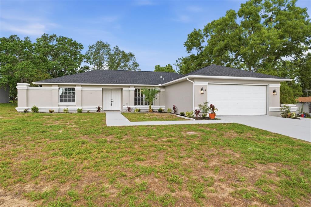 A single-story house with a white garage, gray exterior, and a front walkway — 2489 AMHERST AVENUE, SPRING HILL, FL