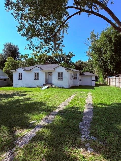 A white single-story house with a detached garage sits on a grassy lot — 2312 BUTLER STREET, LEESBURG, FL