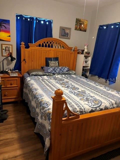 A bedroom features a wooden bed frame, blue curtains, and a nightstand on a wood floor — 2312 BUTLER STREET, LEESBURG, FL