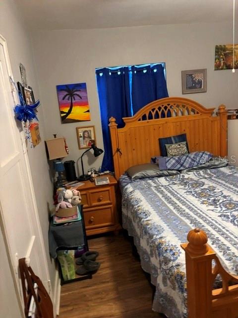 A bedroom features a wooden bed frame, a nightstand, and blue curtains over a window — 2312 BUTLER STREET, LEESBURG, FL