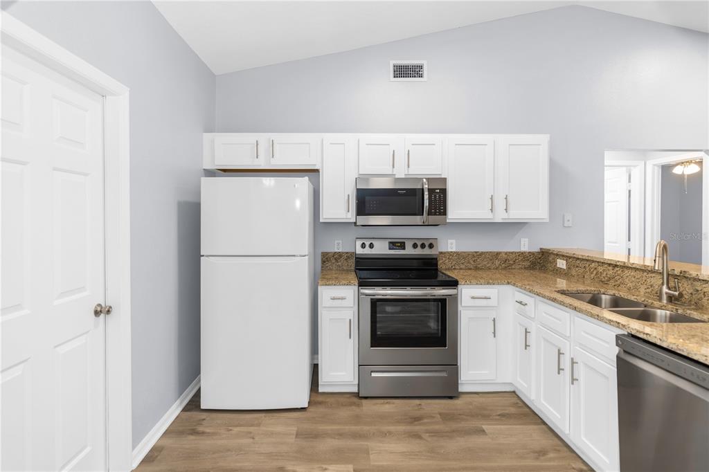 A kitchen with white cabinets, stainless steel appliances, and granite countertops — 17020 WOODCREST WAY, CLERMONT, FL
