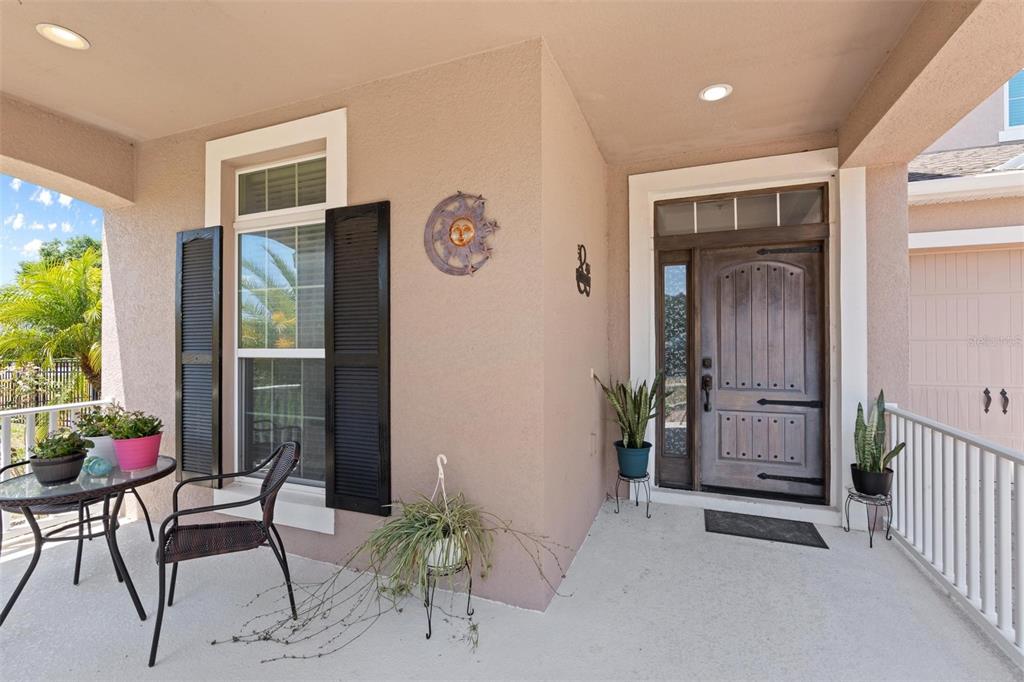 A covered front porch features a wooden door, a window with black shutters, and potted plants — 1204 LEXINGTON AVENUE, DAVENPORT, FL