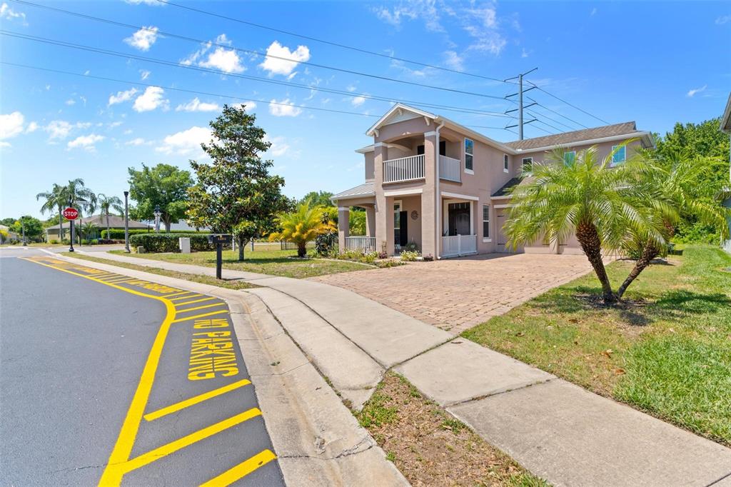 A two-story beige house with a brick driveway and a balcony stands near a street — 1204 LEXINGTON AVENUE, DAVENPORT, FL