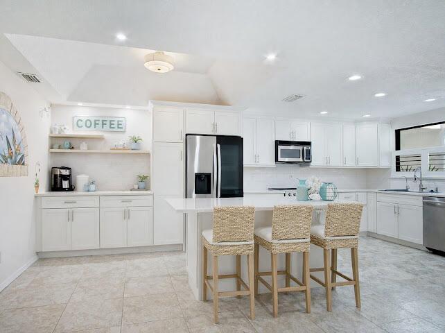 A bright kitchen features white cabinetry, stainless steel appliances, a center island, and tiled floors — 6081 SE Landing Way # 6, Stuart FL 34997, STUART, FL