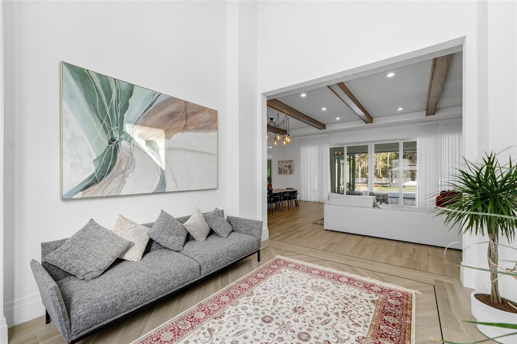 A modern living room features a grey sofa, a patterned rug, and a large painting — 16848 VINCI WAY, BELLA COLLINA, FL