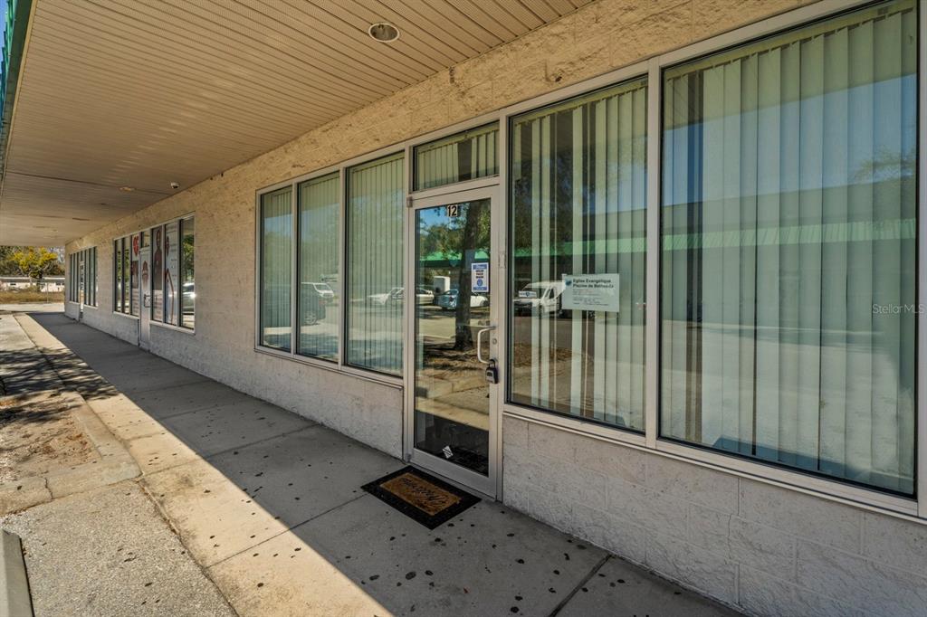 The exterior of a commercial building features a glass entrance door and large storefront windows — 3239 OLD WINTER GARDEN ROAD UNIT 12A/12B, ORLANDO, FL