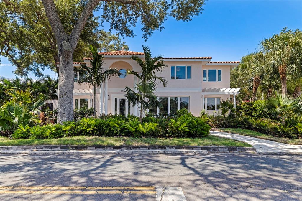 A two-story stucco house with a tiled roof, arched entryway, and lush tropical landscaping — 1846 COFFEE POT BOULEVARD NE, ST PETERSBURG, FL