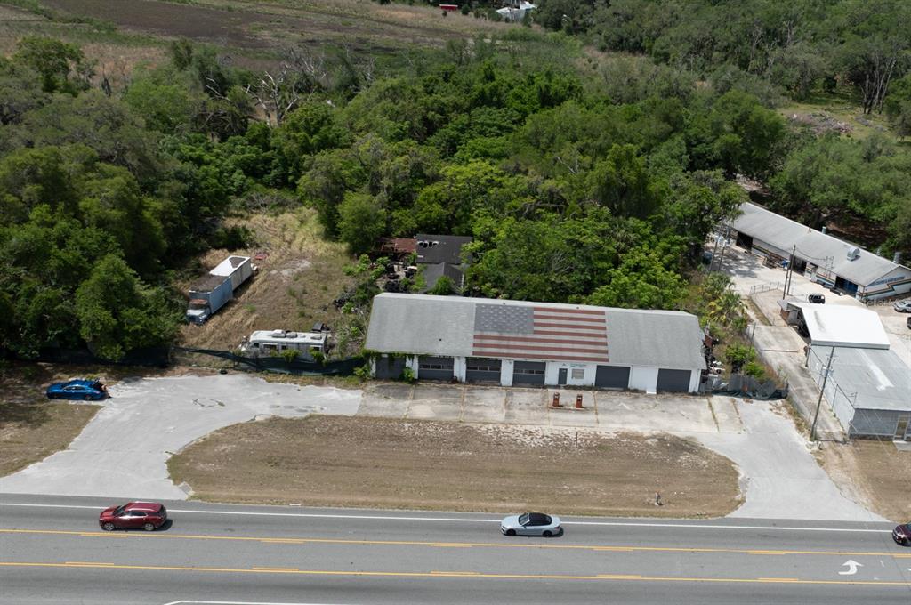 An aerial view shows a commercial building with a flag mural on its roof — 70 N FLORIDA AVENUE, INVERNESS, FL