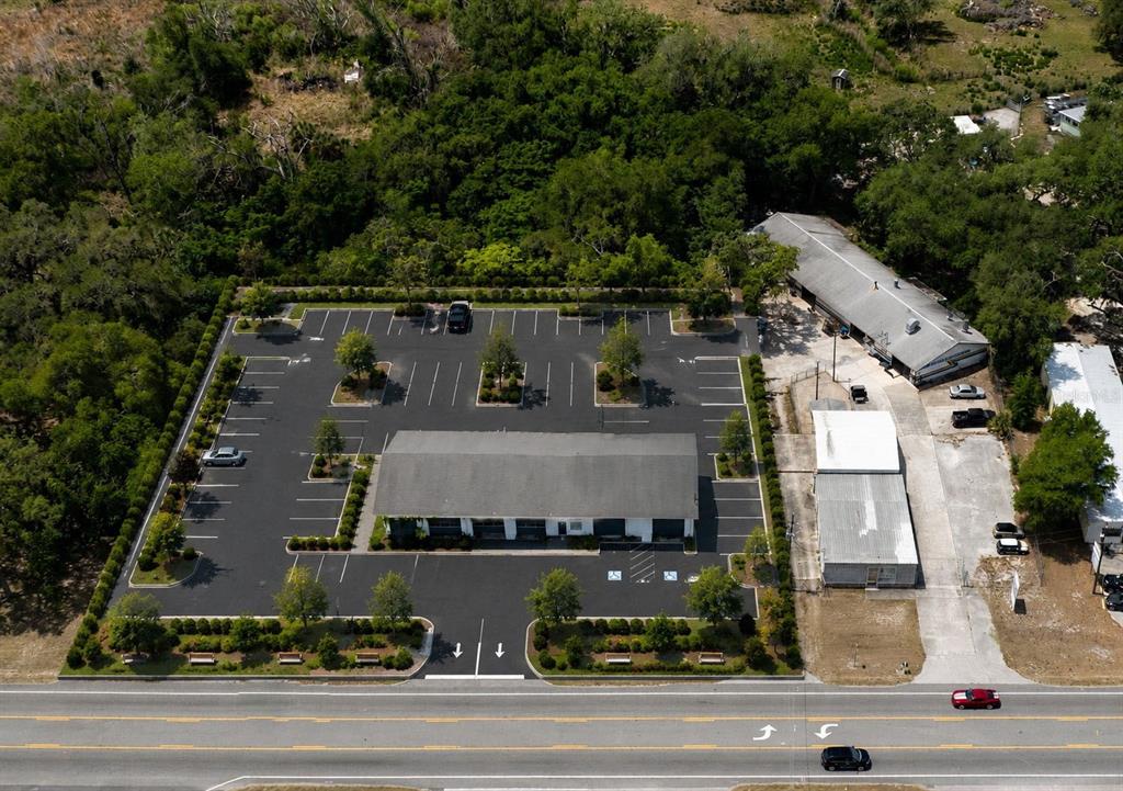 An aerial view shows a commercial building with a large parking lot and surrounding trees — 70 N FLORIDA AVENUE, INVERNESS, FL