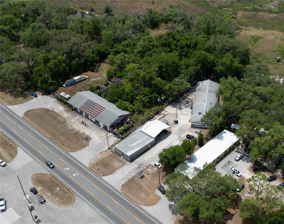 An aerial view shows several commercial buildings with metal roofs situated along a paved road — 70 N FLORIDA AVENUE, INVERNESS, FL