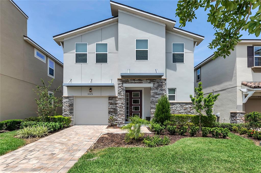 A two-story house with a stone-accented facade, a single-car garage, and a paved driveway — 9029 FLAMINGO KEY WAY, KISSIMMEE, FL