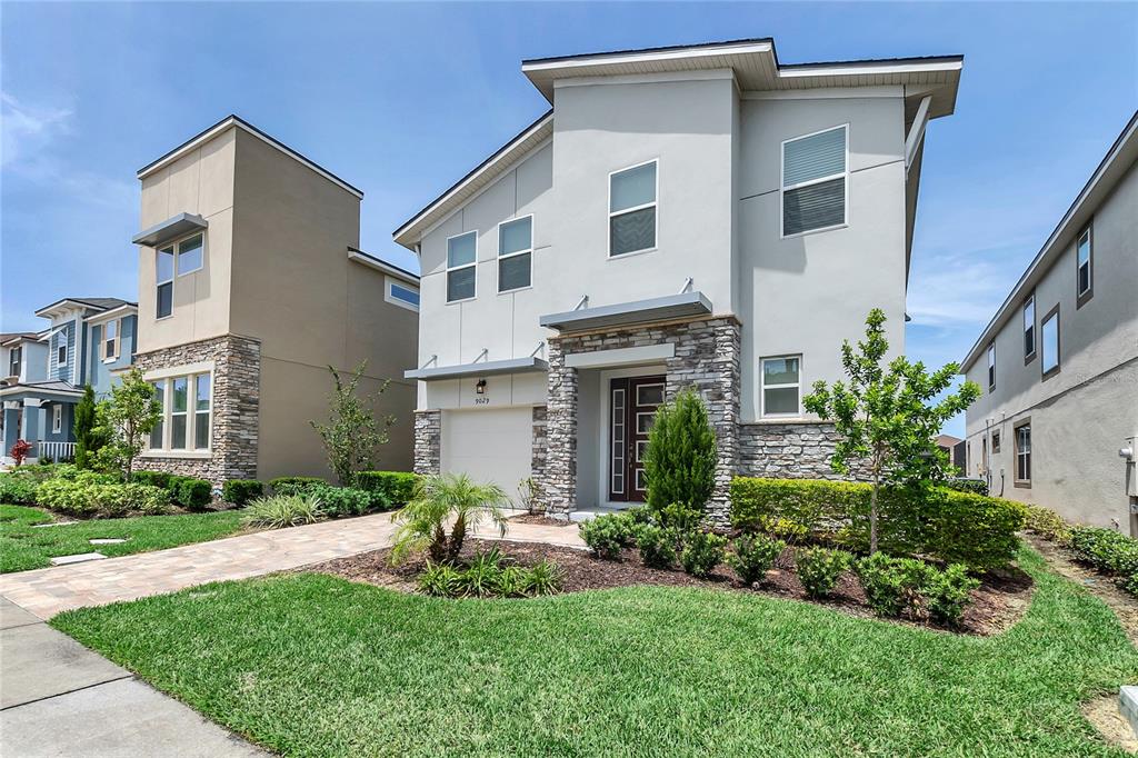 A two-story house with a stone-accented facade, a paved driveway, and a manicured front lawn — 9029 FLAMINGO KEY WAY, KISSIMMEE, FL