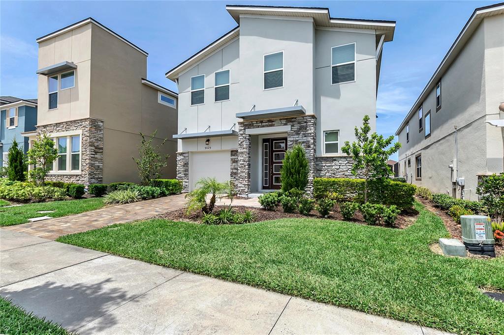 A two-story house with a stone facade, a garage, and a landscaped front yard — 9029 FLAMINGO KEY WAY, KISSIMMEE, FL