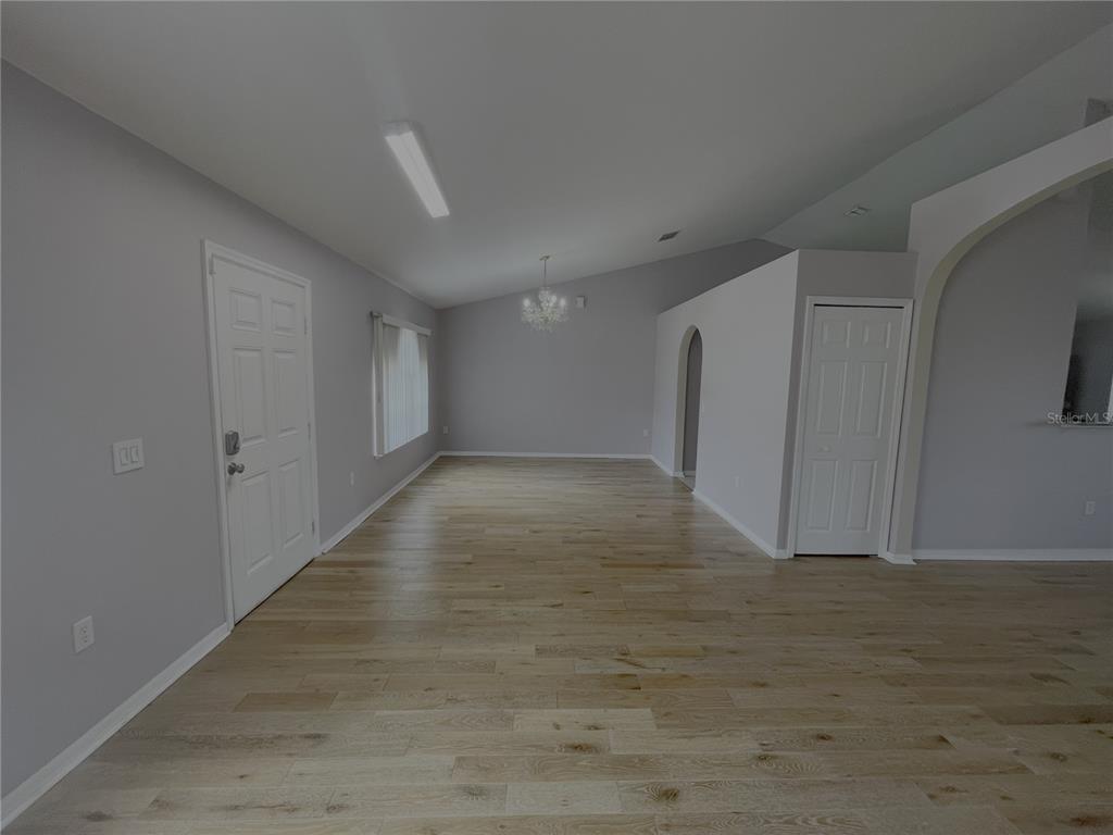 An empty room with light gray walls, wood-look flooring, a chandelier, and a white door — 4535 SW 42ND STREET, OCALA, FL