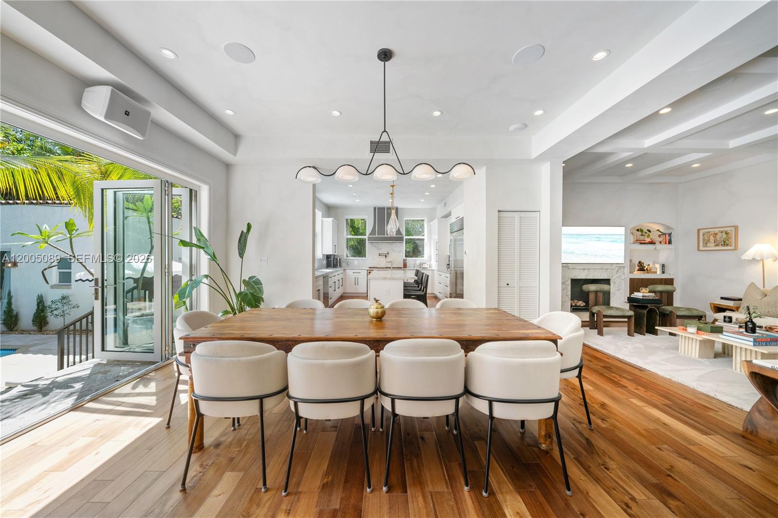 A dining room with a wooden table, white chairs, and an open-concept kitchen beyond — 130 NE 45th St, Miami FL 33137, MIAMI, FL