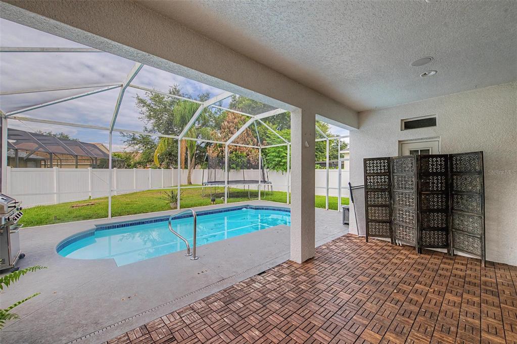 A covered patio features wood-look tiles, a swimming pool, and a screened-in backyard enclosure — 2535 CROSS MORE STREET, VALRICO, FL