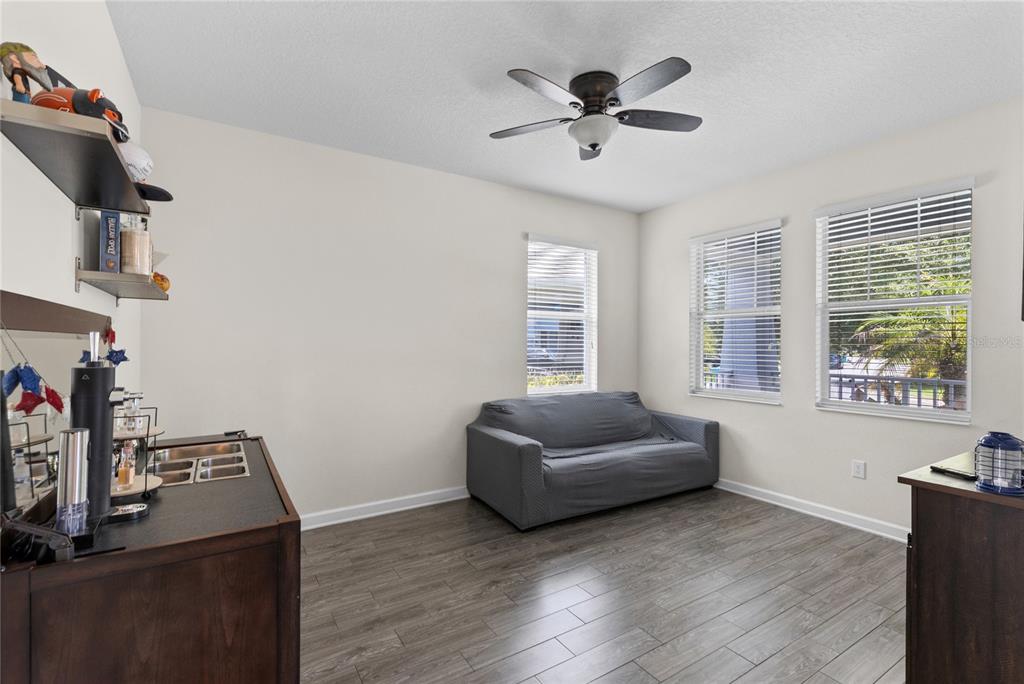 A room with wood-look flooring, a gray sofa, a ceiling fan, and a wet bar — 12016 FICTION AVENUE, ORLANDO, FL
