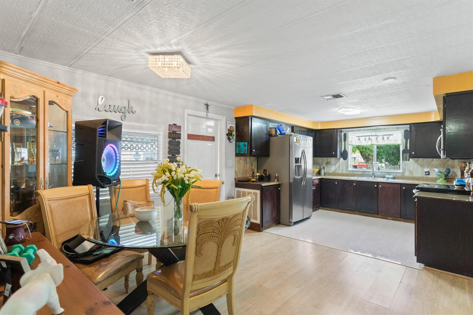 A dining area with a glass table and chairs opens into a kitchen with dark cabinets — 2961 SW 52nd Terrace, Davie FL 33314, DAVIE, FL