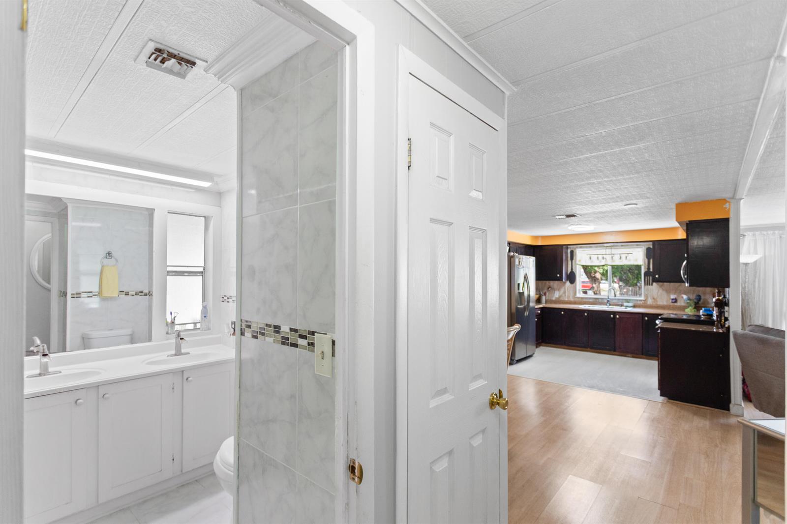 A view from a tiled bathroom looking through a doorway into a kitchen with cabinets — 2961 SW 52nd Terrace, Davie FL 33314, DAVIE, FL