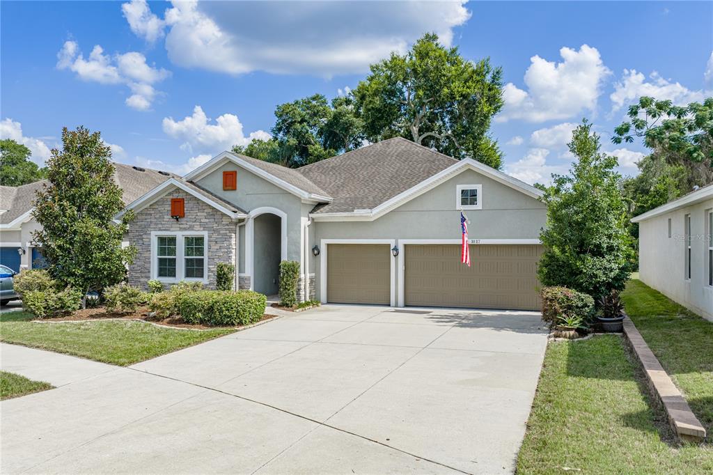 A single-story house with a stone-accented facade, a two-car garage, and a concrete driveway — 1017 TRACEY ANN LOOP, SEFFNER, FL
