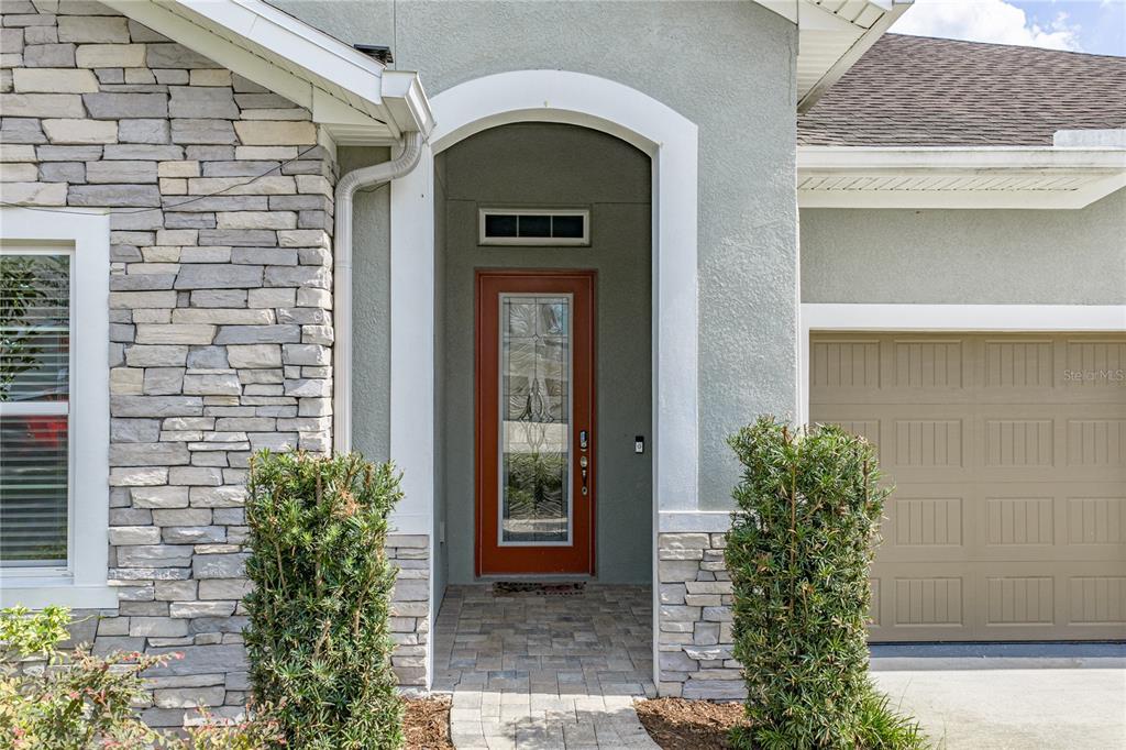 The exterior of a house features a stone facade, a tan garage door, and an entryway — 1017 TRACEY ANN LOOP, SEFFNER, FL