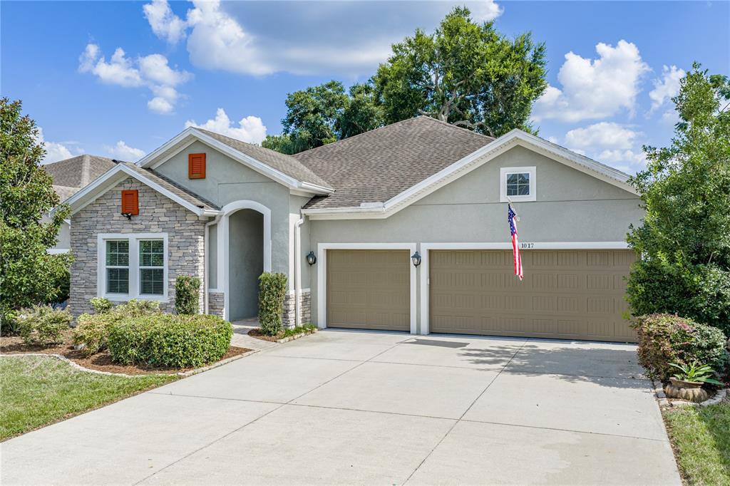 A single-story house with a stone facade, beige stucco, and a three-car garage — 1017 TRACEY ANN LOOP, SEFFNER, FL