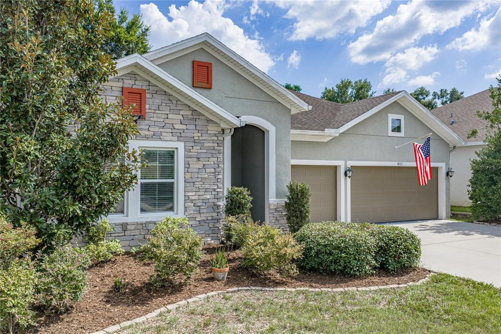 A single-story house features a stone facade, stucco walls, and a two-car garage — 1017 TRACEY ANN LOOP, SEFFNER, FL