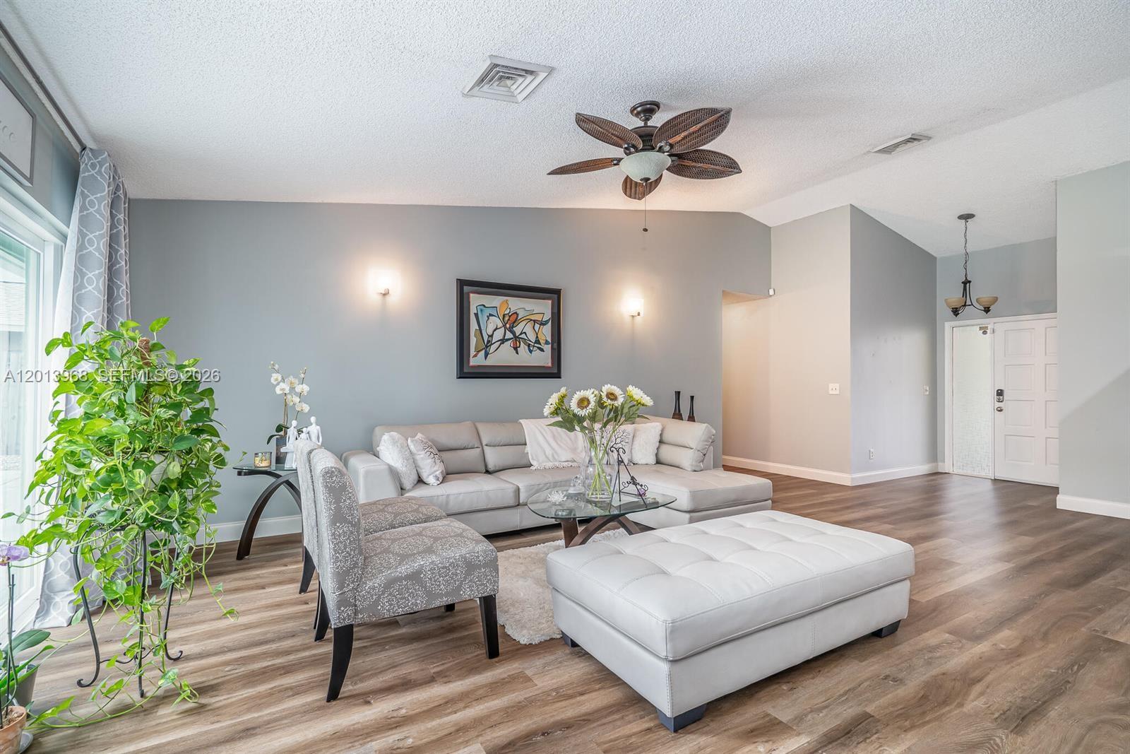 A living room features a light gray sectional sofa, patterned chairs, and wood-look flooring — 4125 NW 96th Ter # 4125, Sunrise FL 33351, SUNRISE, FL