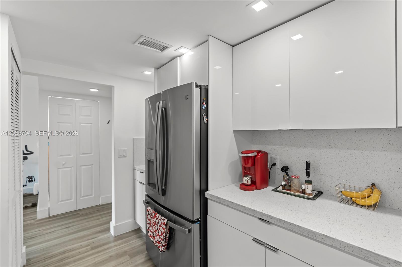 A modern kitchen features white glossy cabinets, a stainless steel refrigerator, and speckled countertops — 2055 SW 122nd Ave # 326, Miami FL 33175, MIAMI, FL