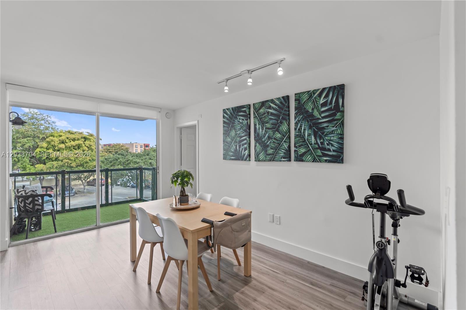 A dining area features a wooden table, white chairs, wall art, and a balcony view — 2055 SW 122nd Ave # 326, Miami FL 33175, MIAMI, FL
