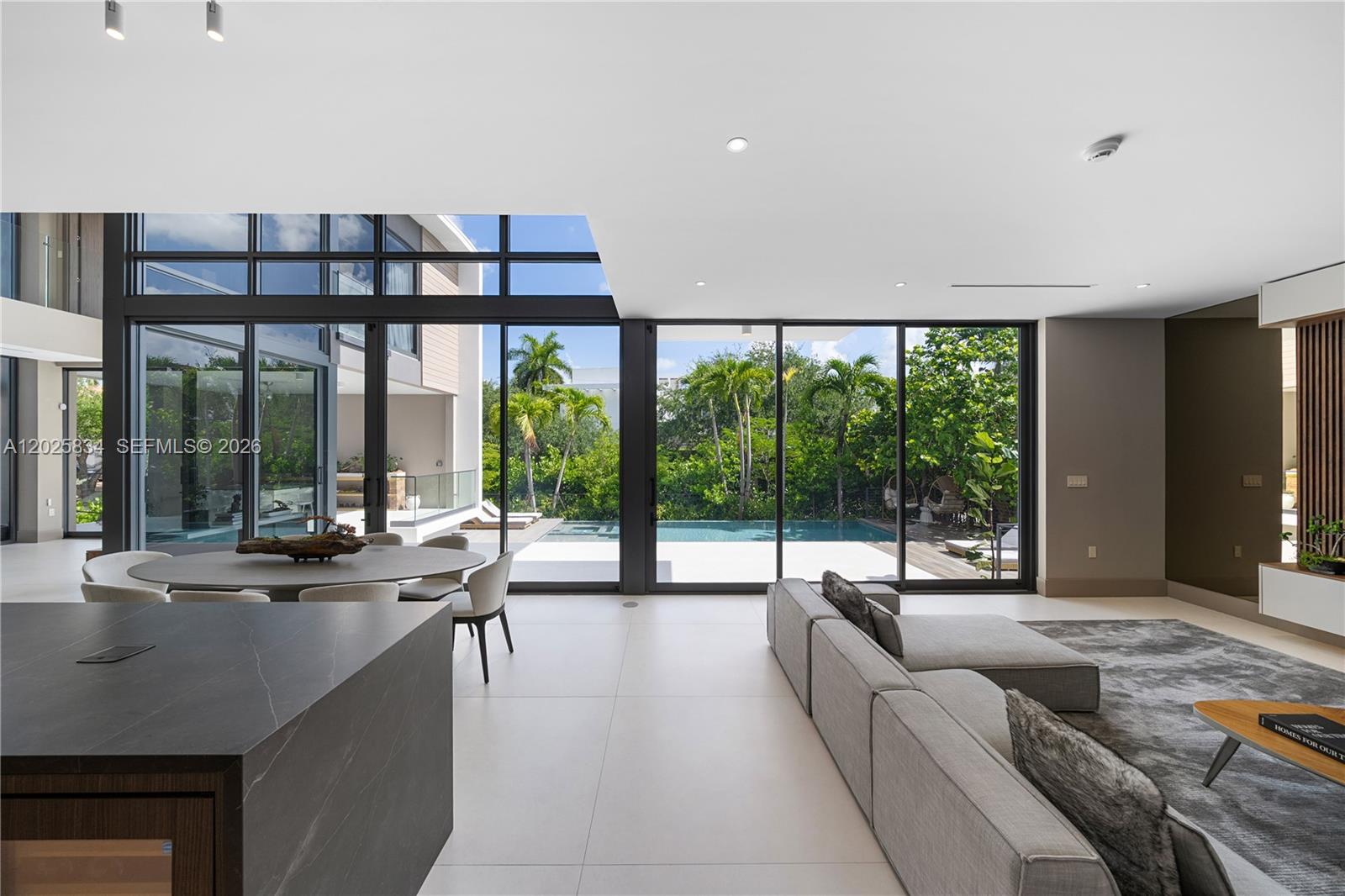 A modern living and dining area features floor-to-ceiling windows overlooking a patio and pool — 571 Glenridge Rd, Key Biscayne FL 33149, KEY BISCAYNE, FL