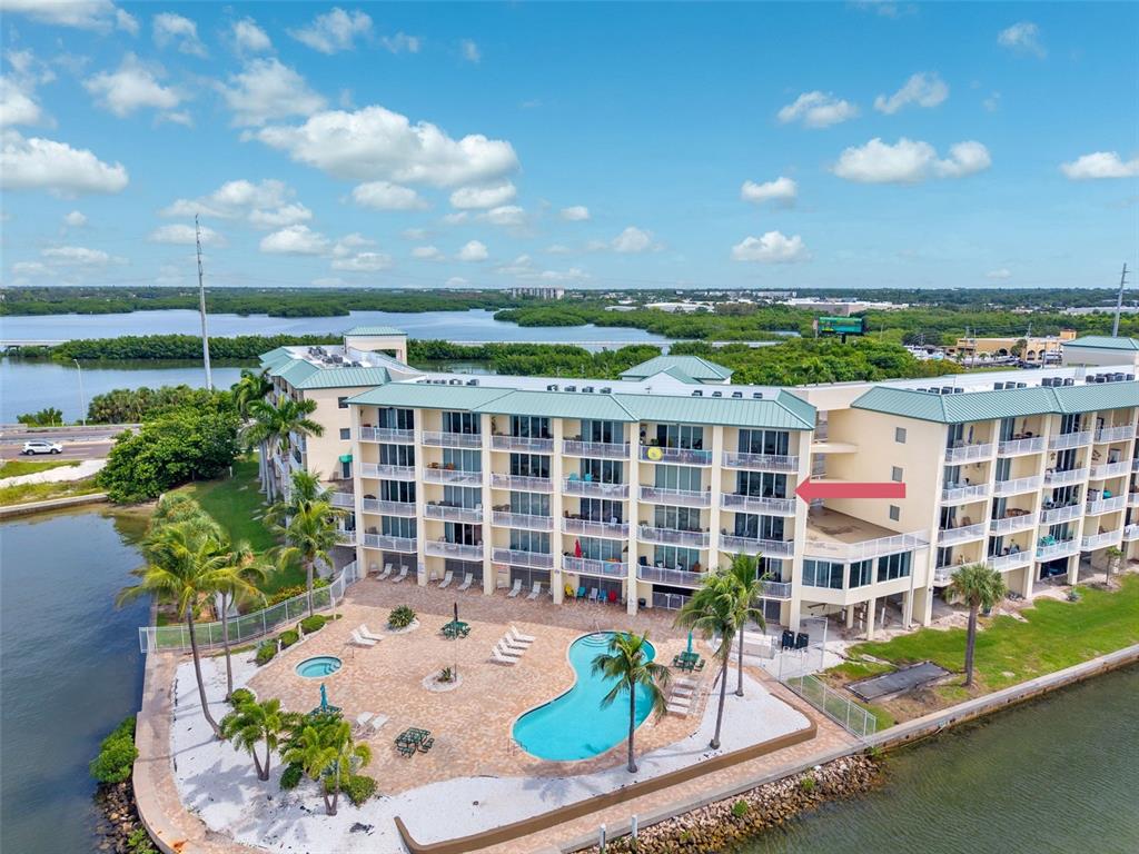 An aerial view of a multi-story waterfront apartment building with a swimming pool and patio — 8800 BAY PINES BOULEVARD UNIT 312, ST PETERSBURG, FL