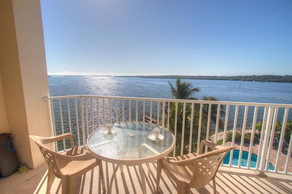 A balcony with a glass-top table and two chairs overlooks a body of water — 8800 BAY PINES BOULEVARD UNIT 312, ST PETERSBURG, FL