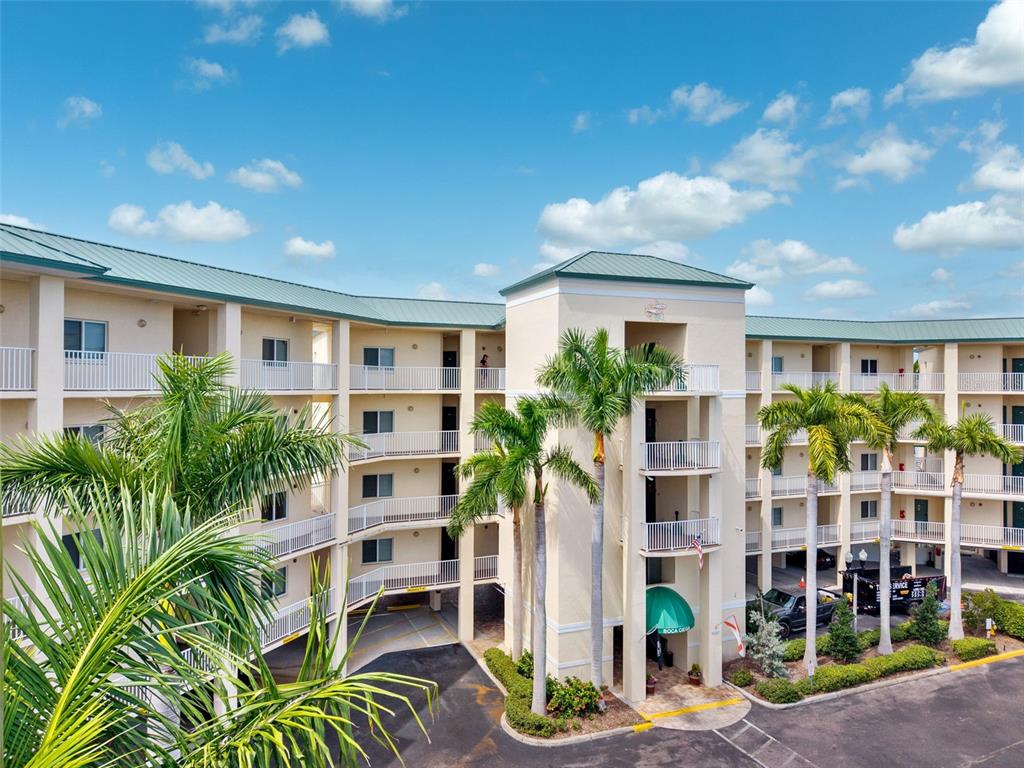 An exterior view of a multi-story apartment building with palm trees and a covered entrance — 8800 BAY PINES BOULEVARD UNIT 312, ST PETERSBURG, FL