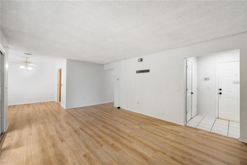 An open living area features light wood-look flooring, white walls, and a tiled entryway — 4160 VERSAILLES DRIVE UNIT 4160D, ORLANDO, FL
