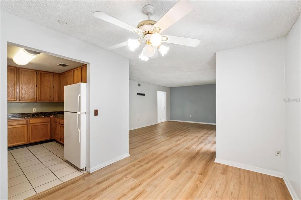 A dining area with wood-look flooring leads to a kitchen with white appliances and cabinets — 4160 VERSAILLES DRIVE UNIT 4160D, ORLANDO, FL