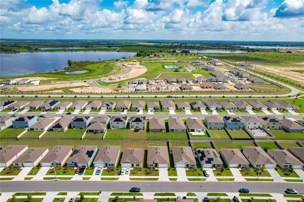 An aerial view shows a suburban neighborhood with rows of houses near a large lake — 276 SOFIA LANE, LAKE ALFRED, FL