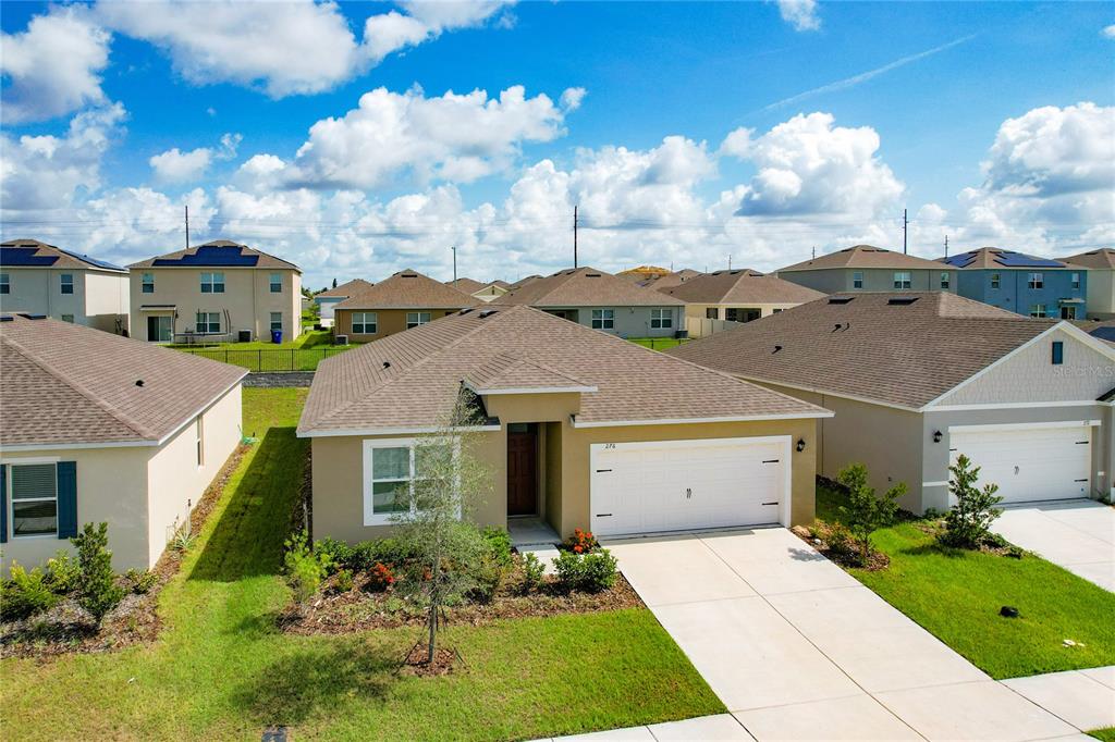 An aerial view of a single-story suburban house with a tan exterior and two-car garage — 276 SOFIA LANE, LAKE ALFRED, FL