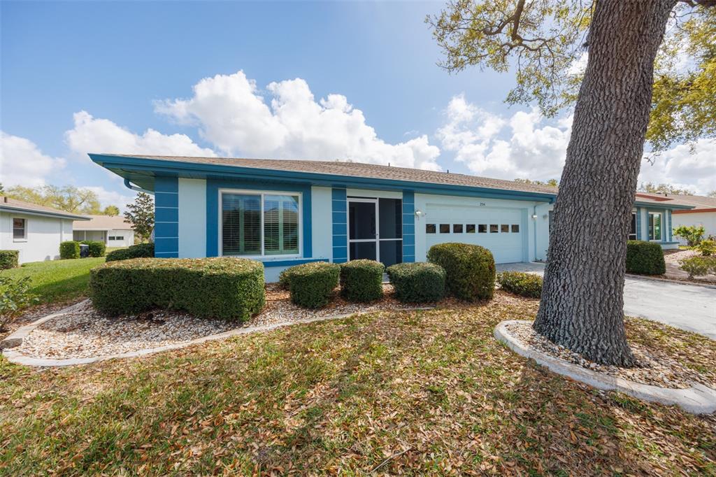 A spacious living area with light gray walls, wood-look flooring, and a pass-through to the kitchen — 2514 LOCKSLEY STREET, SUN CITY CENTER, FL
