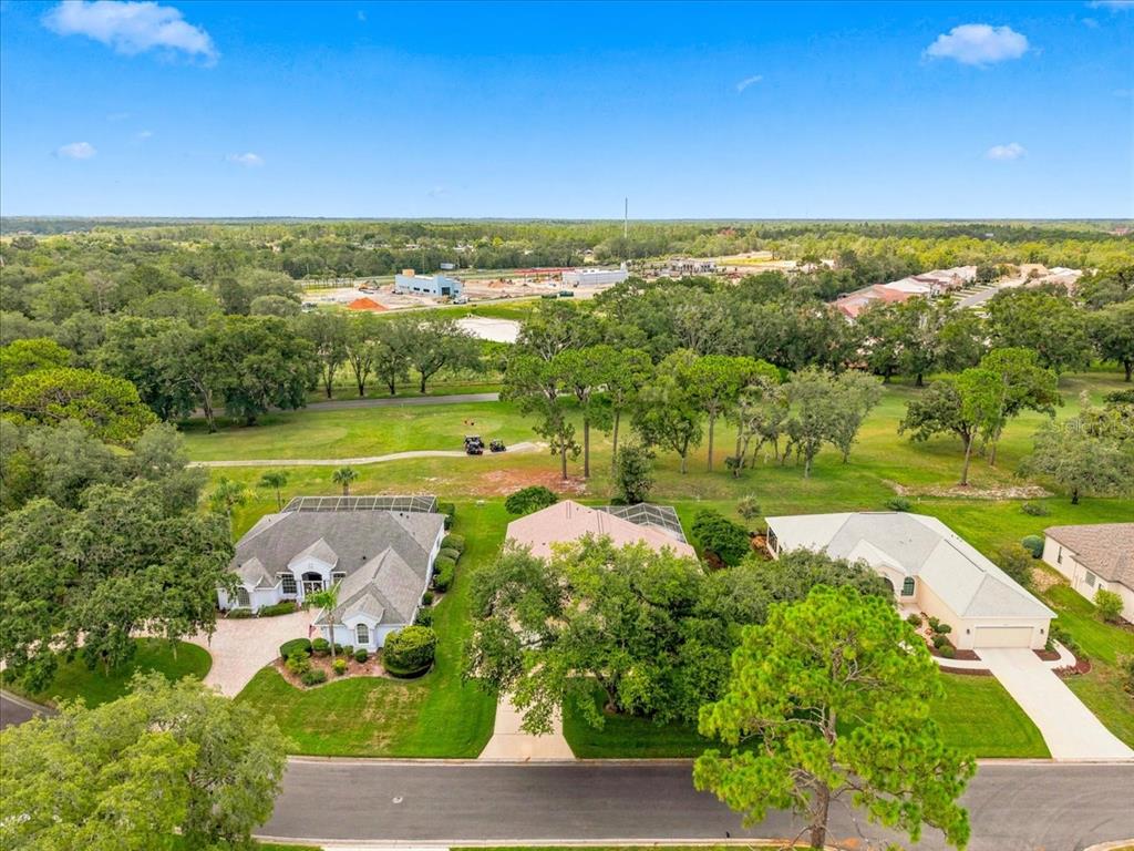 An aerial view of three suburban houses bordering a golf course with trees and grass — 9720 SOUTHERN BELLE DRIVE, WEEKI WACHEE, FL