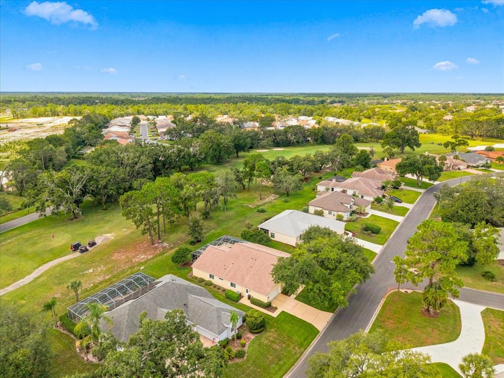 An aerial view shows several suburban houses with pools along a street near a golf course — 9720 SOUTHERN BELLE DRIVE, WEEKI WACHEE, FL