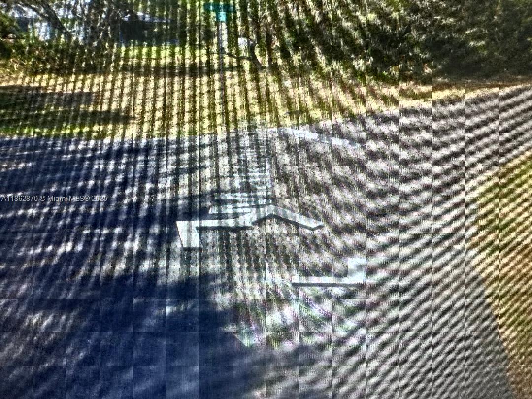 A paved road intersection features a white painted "MALCOLM" street name and directional arrows — 15248 Malcom ave, Port Charlotte FL 33954, PORT CHARLOTTE, FL