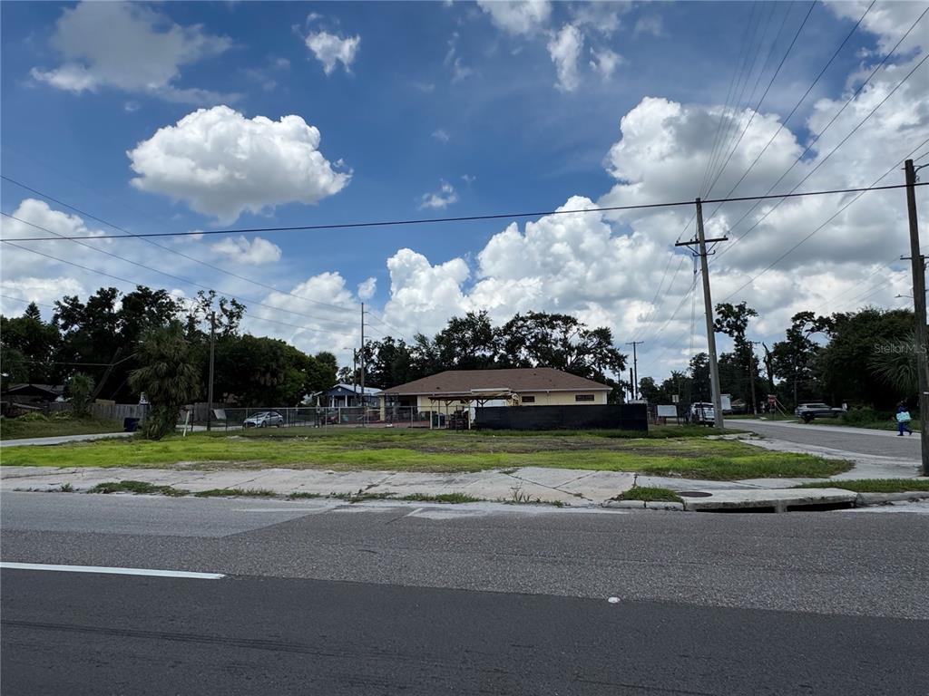 A vacant, grassy lot sits in front of a single-story building with a chain-link fence — 2804 E COLUMBUS DRIVE, TAMPA, FL