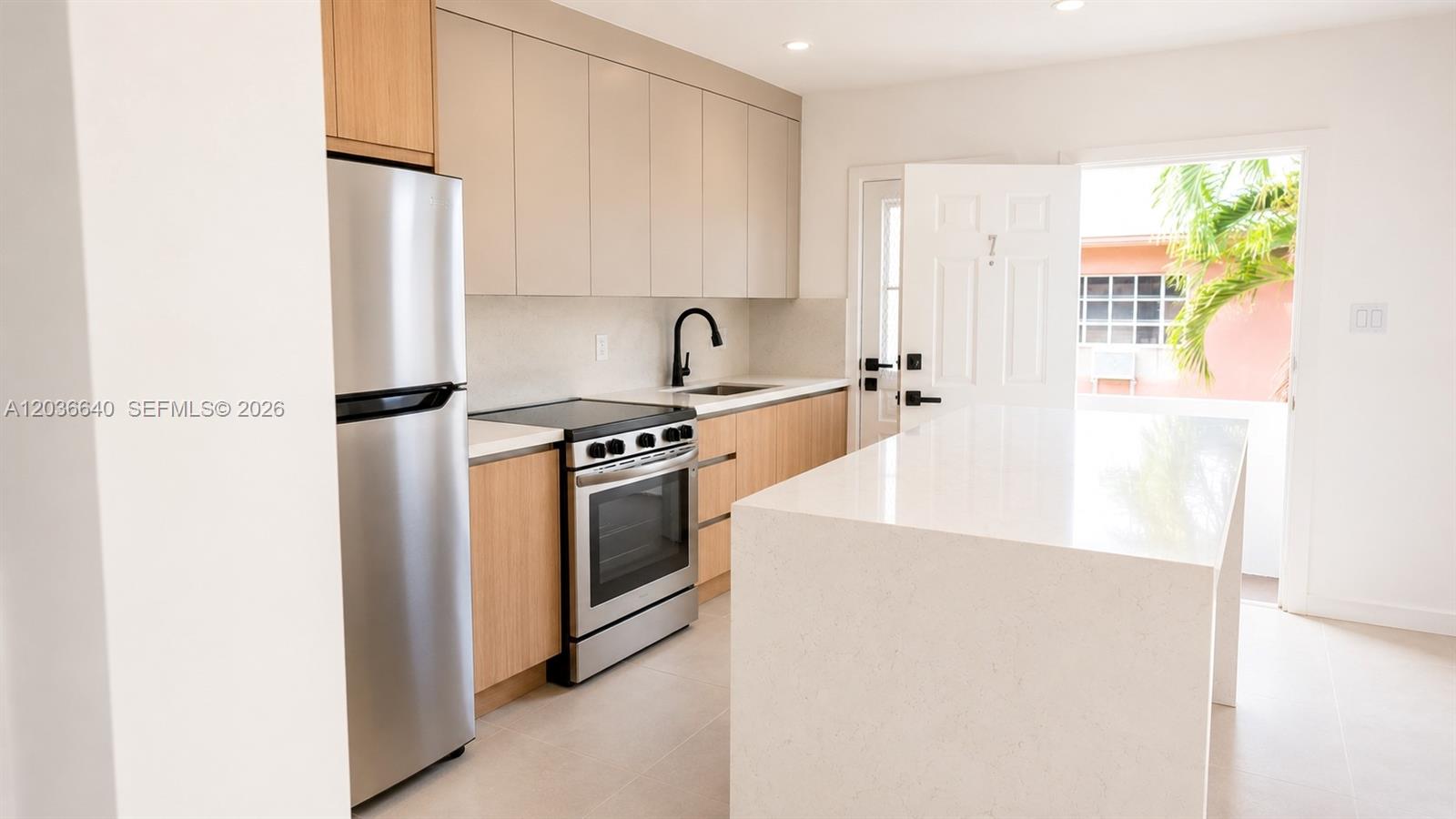 A modern kitchen features light wood cabinets, stainless steel appliances, and a white quartz island — 550 SW 10th St # 7, Miami FL 33130, MIAMI, FL
