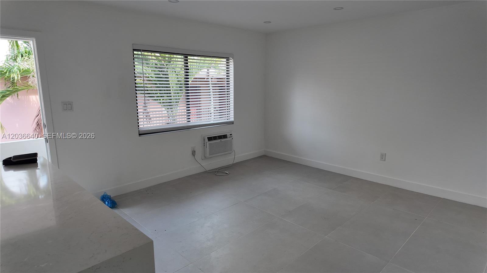 A minimalist room features white walls, large gray floor tiles, and a window air conditioner — 550 SW 10th St # 7, Miami FL 33130, MIAMI, FL