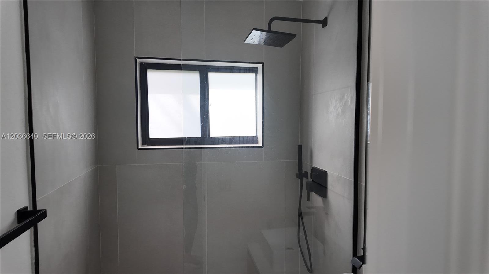 A modern walk-in shower features gray tiled walls, a black rainfall showerhead, and a window — 550 SW 10th St # 7, Miami FL 33130, MIAMI, FL