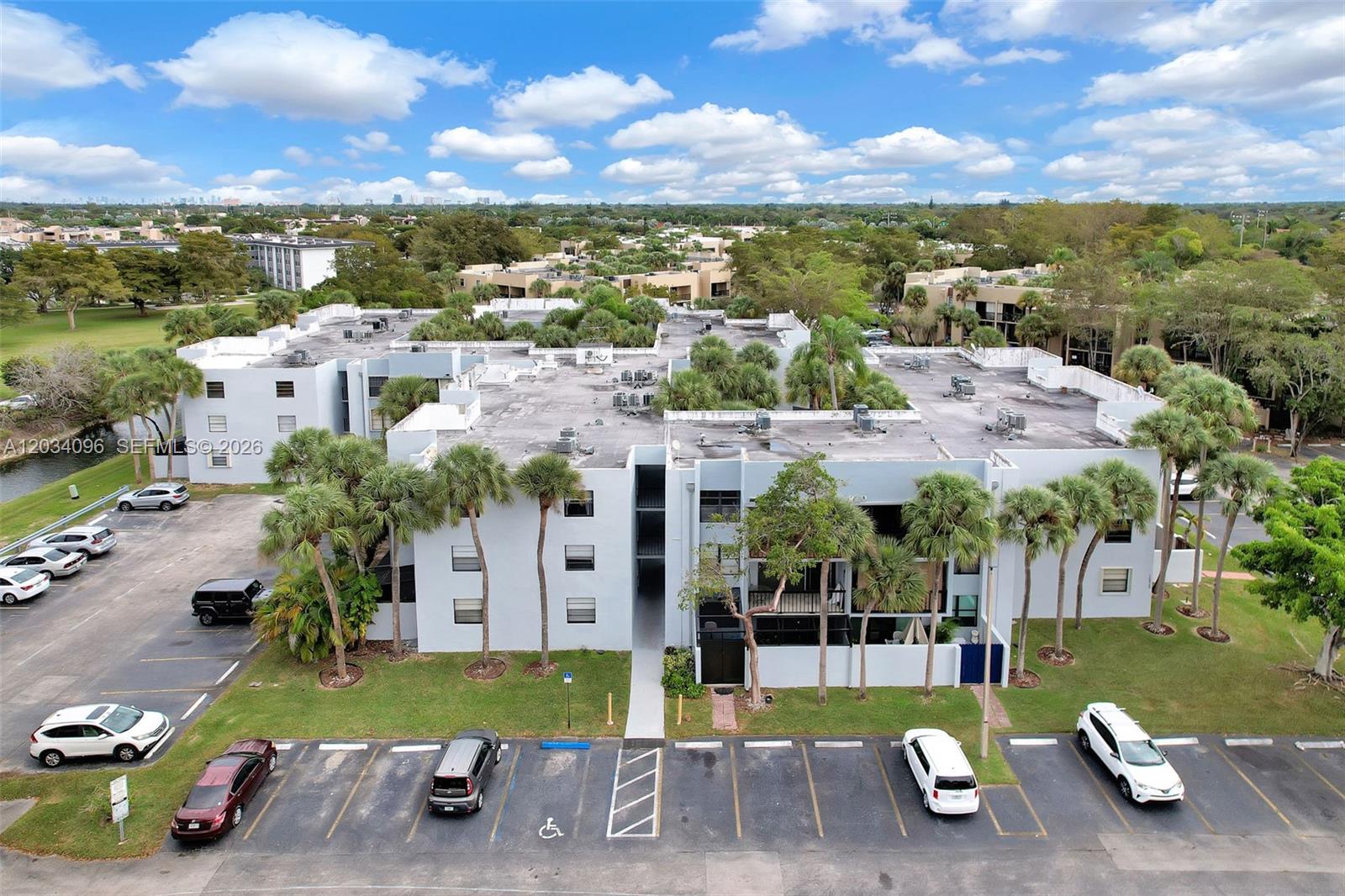 An aerial view shows a multi-story apartment building with a parking lot and palm trees — 10825 SW 112th Ave # 216, Miami FL 33176, MIAMI, FL