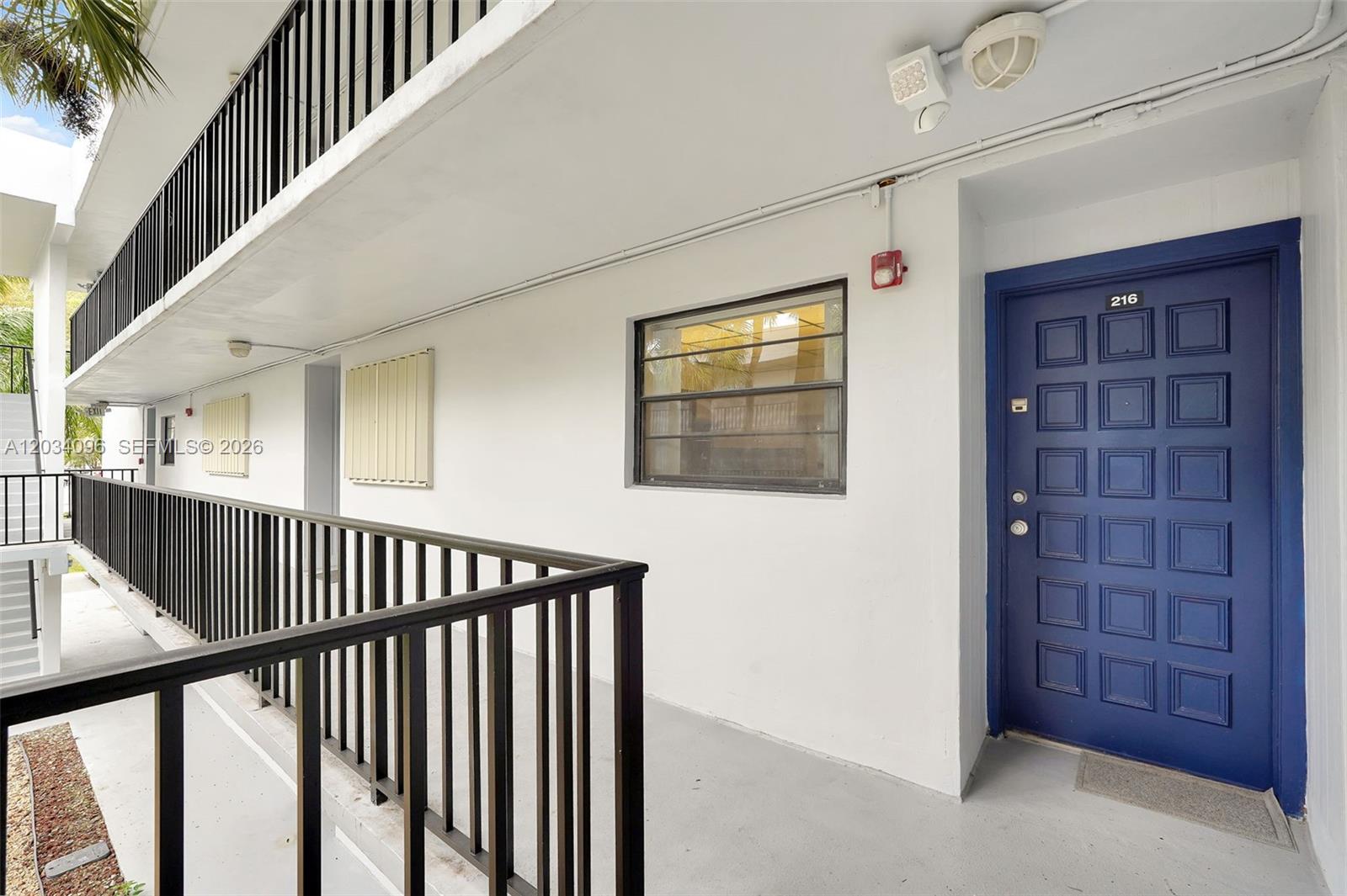 An exterior walkway features a blue door numbered 216, a window, and black metal railings — 10825 SW 112th Ave # 216, Miami FL 33176, MIAMI, FL