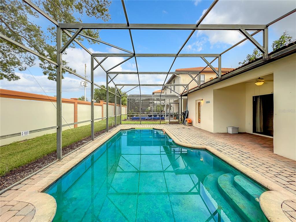 A swimming pool with a screened enclosure sits on a paved patio next to a house — 501 SUMMER PLACE LOOP, CLERMONT, FL
